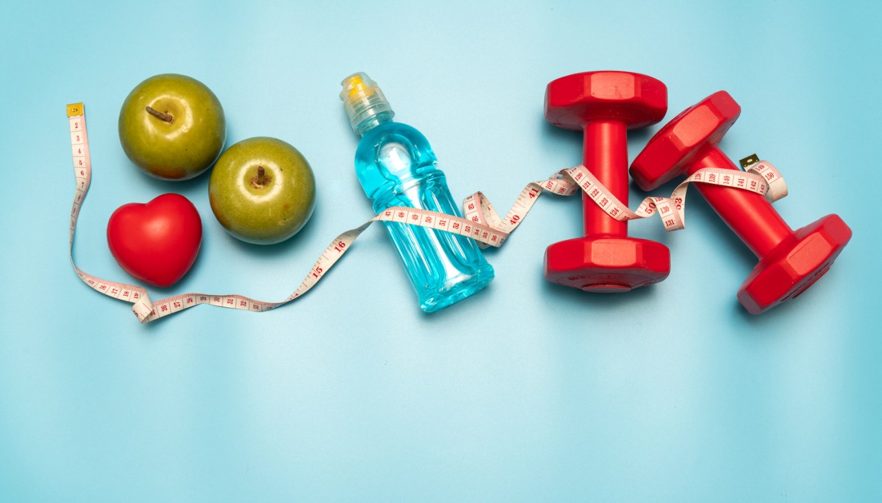 fruit, a water bottle, and weights on a blue background