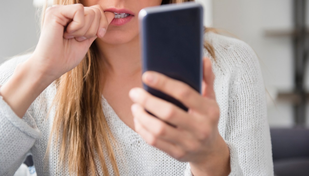 Nervous woman with phone biting nails