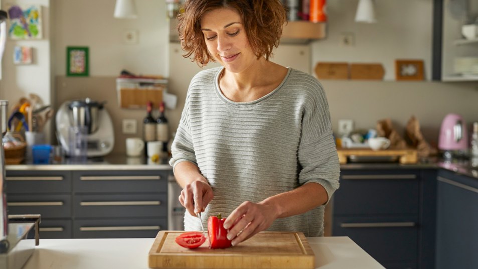 Woman cutting a tomato whilst in her kitchen