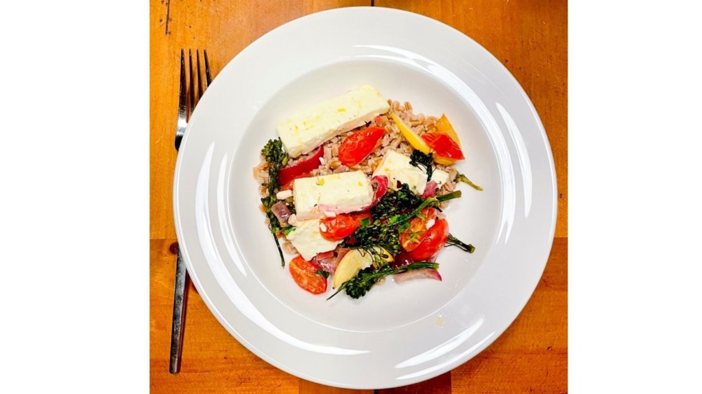 sheet pan dinner with roasted broccoli, tomatoes, lemon, and feta ready to eat on a plate