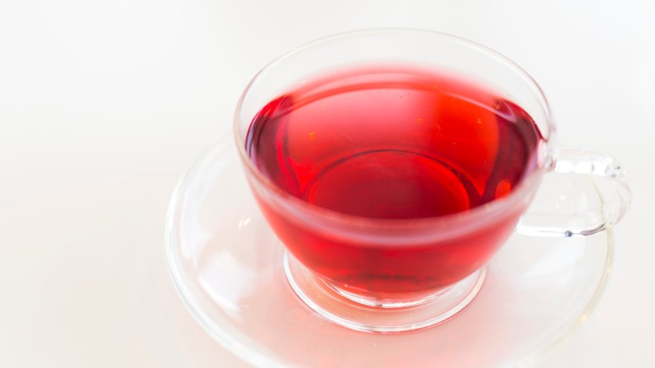 pink watermelon tea in a clear glass cup with a glass saucer