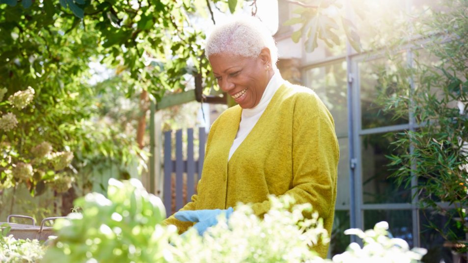 senior woman performing garden prep in her garden, smiling