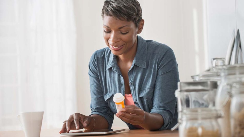 Woman hold a prescription bottle and using her tablet