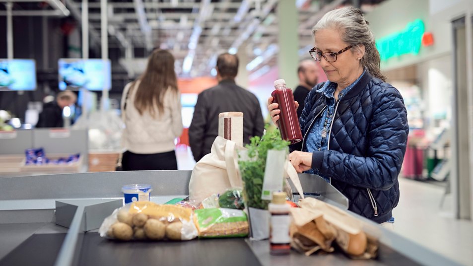 woman buying groceries and bagging them at the checkout stand