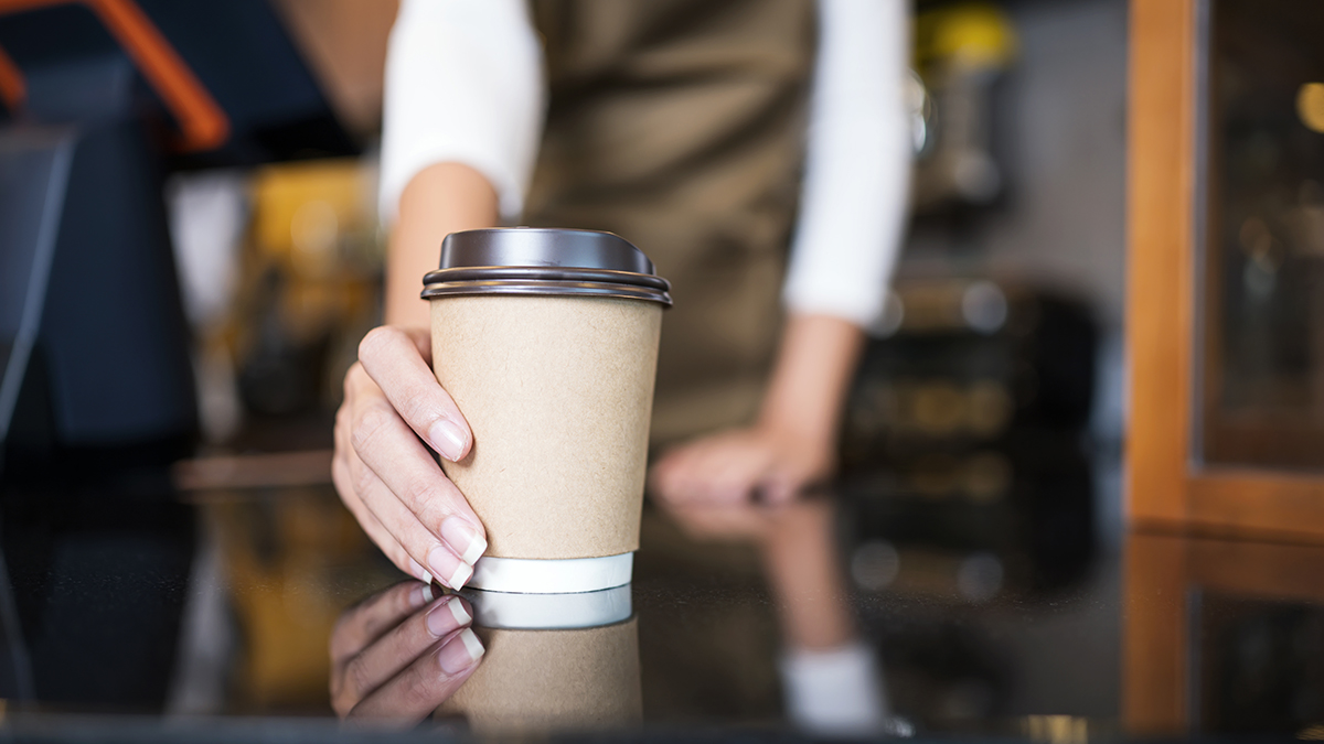 A coffee cup being handed over by a barista and contains a low calorie option