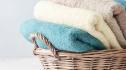 How to fold towels to save space: Bath towels of different colors in wicker basket on light background