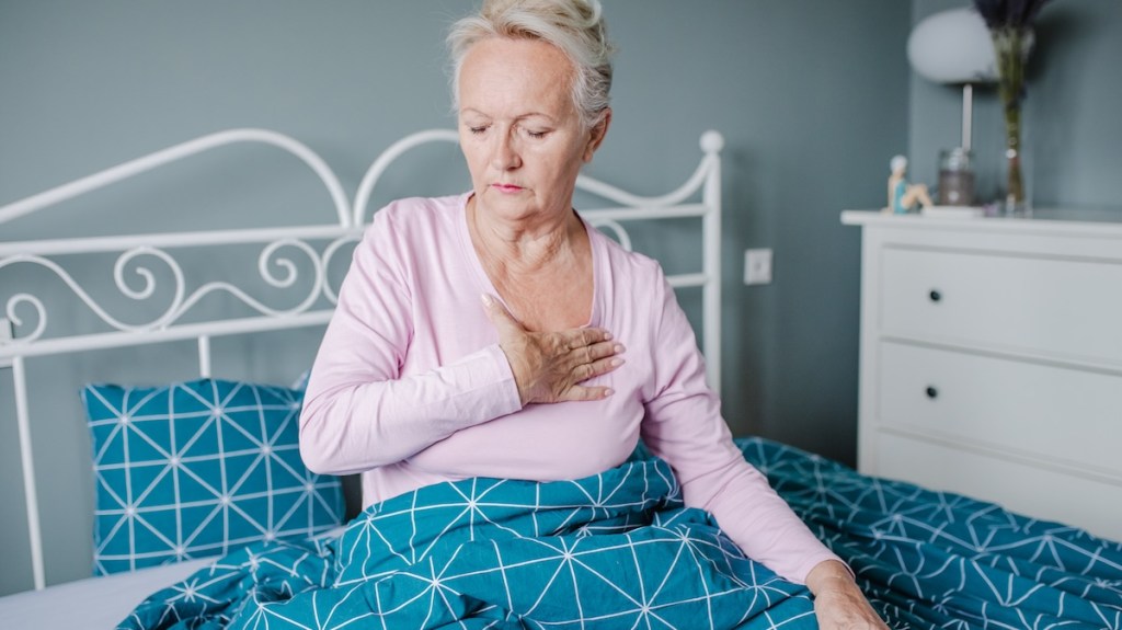 An elderly woman suffering from chest pain in bed.