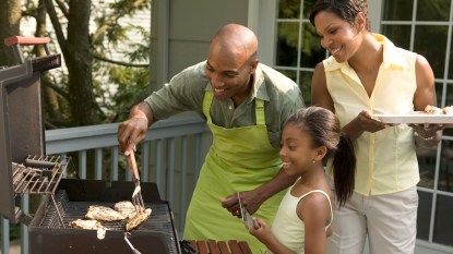 Family of 3 grilling chicken in the backyard