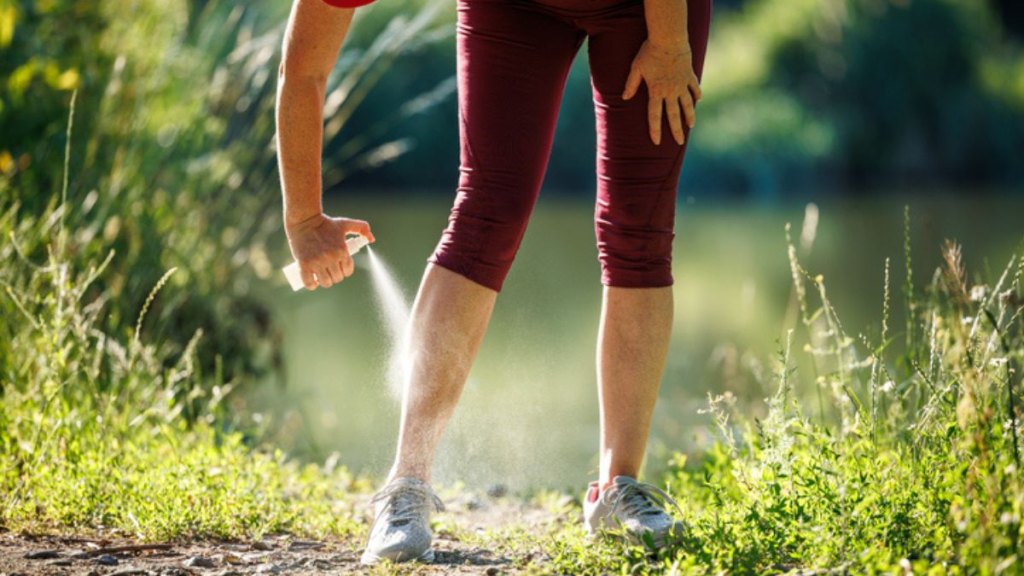 mature woman spraying her legs outside with bug spray to prevent an infected mosquito bite from becoming cellulitis