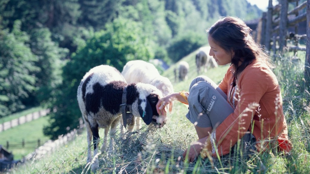 Young woman pets goats on a hillside