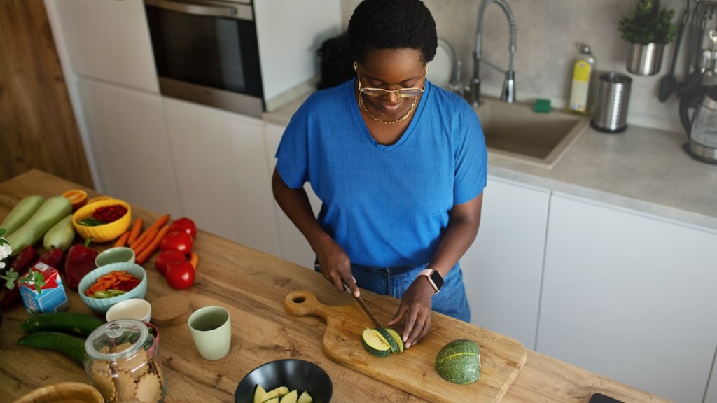 A woman slices vegetables in her kitchen