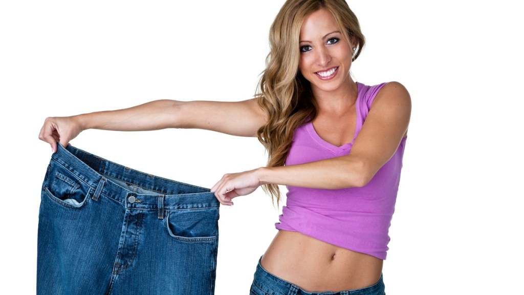 Woman holds up an old pair of too-big jeans