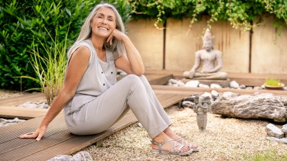 mature woman sitting outside smiling and wearing summer sandals