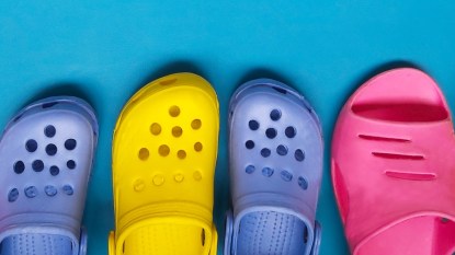 Blue, yellow and pink Crocs, which can sometimes be good for your feet, against a blue background