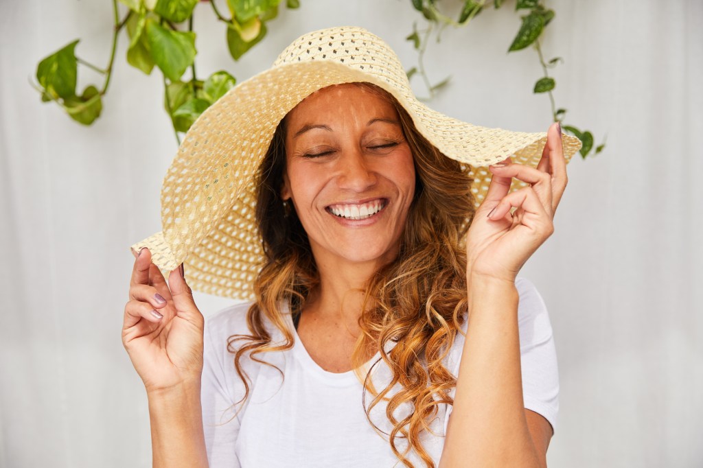 mature woman laughing while wearing sun hat