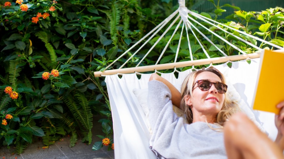 mature woman reading on hammock wearing sunglasses