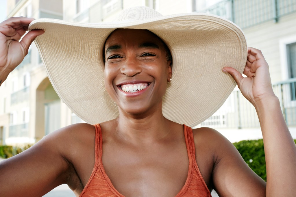 woman wearing wide brimmed sun hat outside smiling