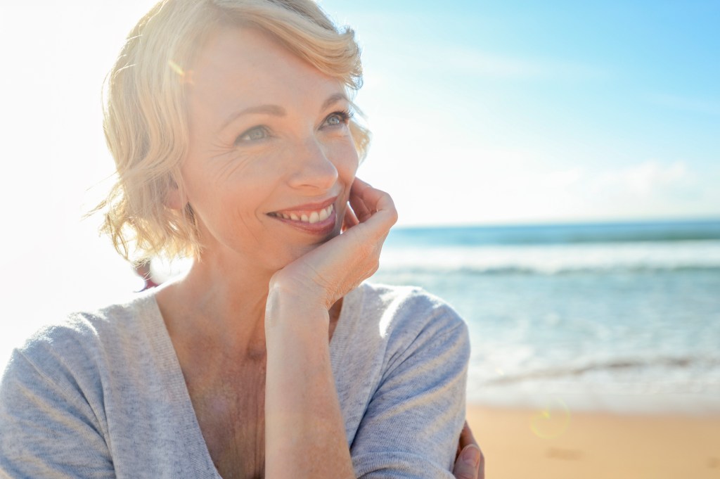 mature woman on the beach smiling in the sun