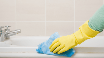 Woman cleaning bathtub with a cloth, which can be used as a DIY disinfectant wipe