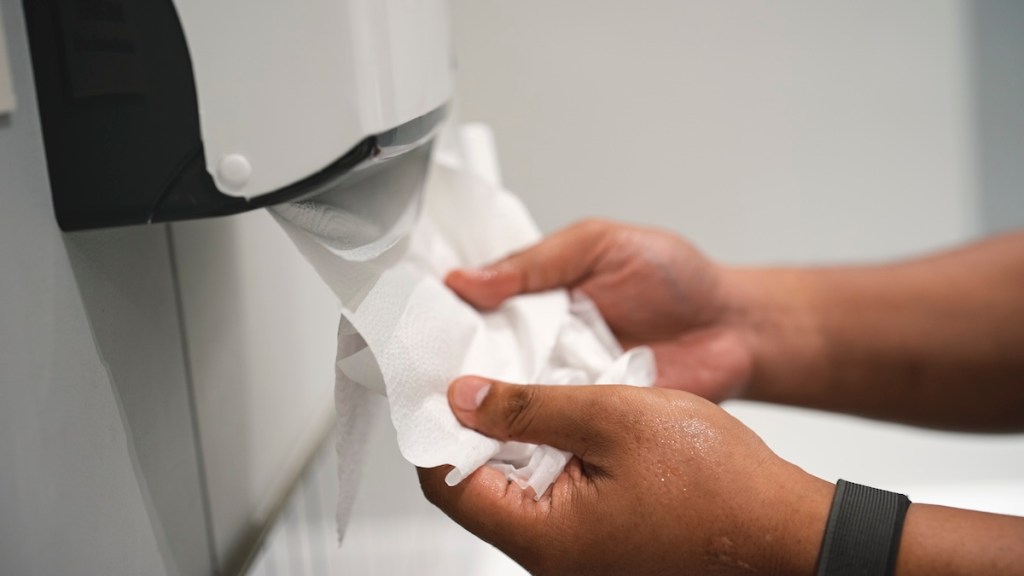 Person pulls toilet paper out of a dispenser