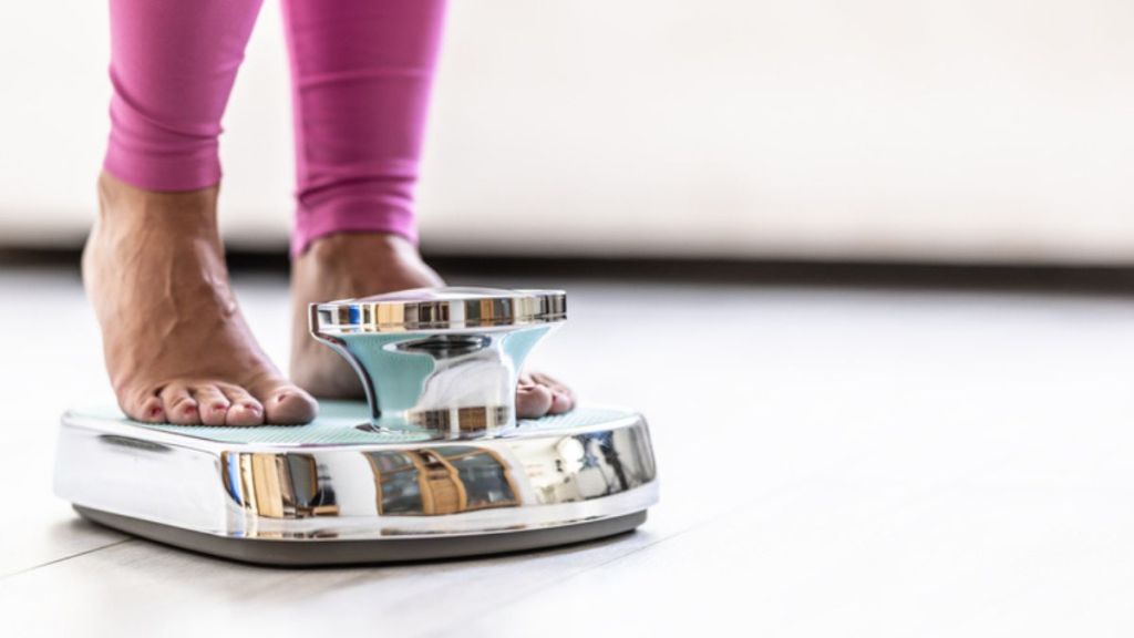 Close-up of a woman standing on scale, which is a common weight loss mistake 