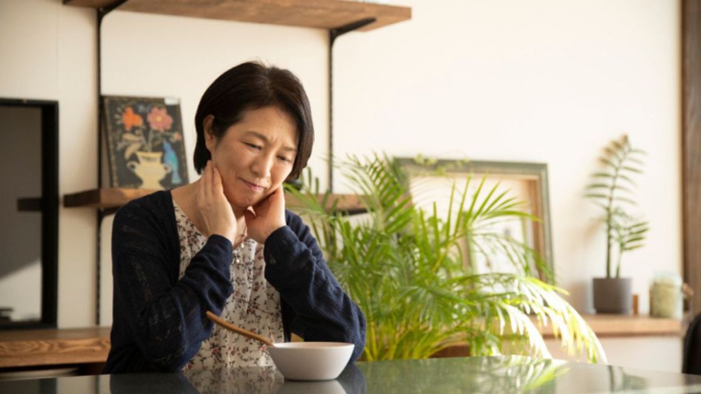 Mature woman looking disappointed while staring at a bowl on her kitchen table