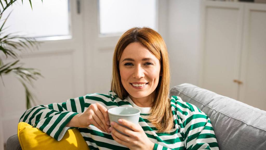 Woman drinking cup of coffee on couch