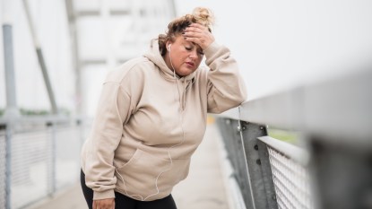 An overweight woman holding her head due to poor sleep, struggling to lose weight on semaglutide