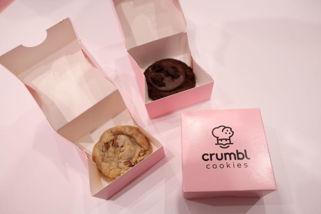 two Crumbl cookies in pink box packaging on pink table