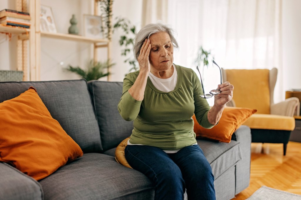 mature woman with dizziness, holding her hand to her head trying to figure out which ear is causing vertigo