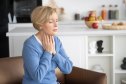 mature woman feeling her neck for early warning signs of thyroid problems at home