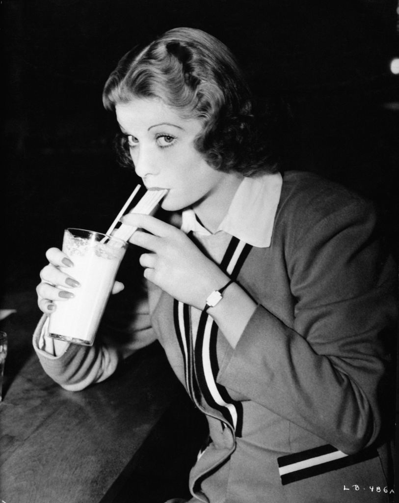 Lucille Ball blowing bubbles in her beverage through a straw on June 8, 1938.