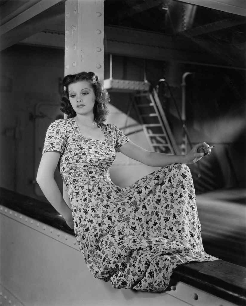 Lucille Ball poses for a seated photograph on the edge of a boat, circa 1930.