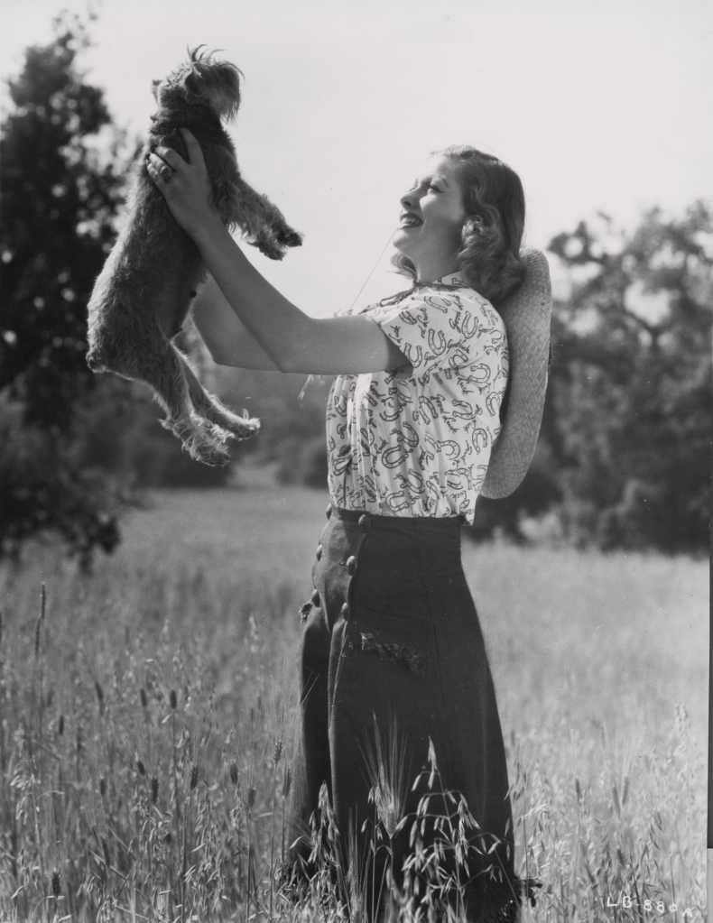 (Original Caption) Lucille Ball poses with pet dog in 1939 in a Good Luck pattern blouse, designed to get the picture of the then budding young RKO star in the papers.