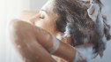 A woman washing her hair with shampoo while showering