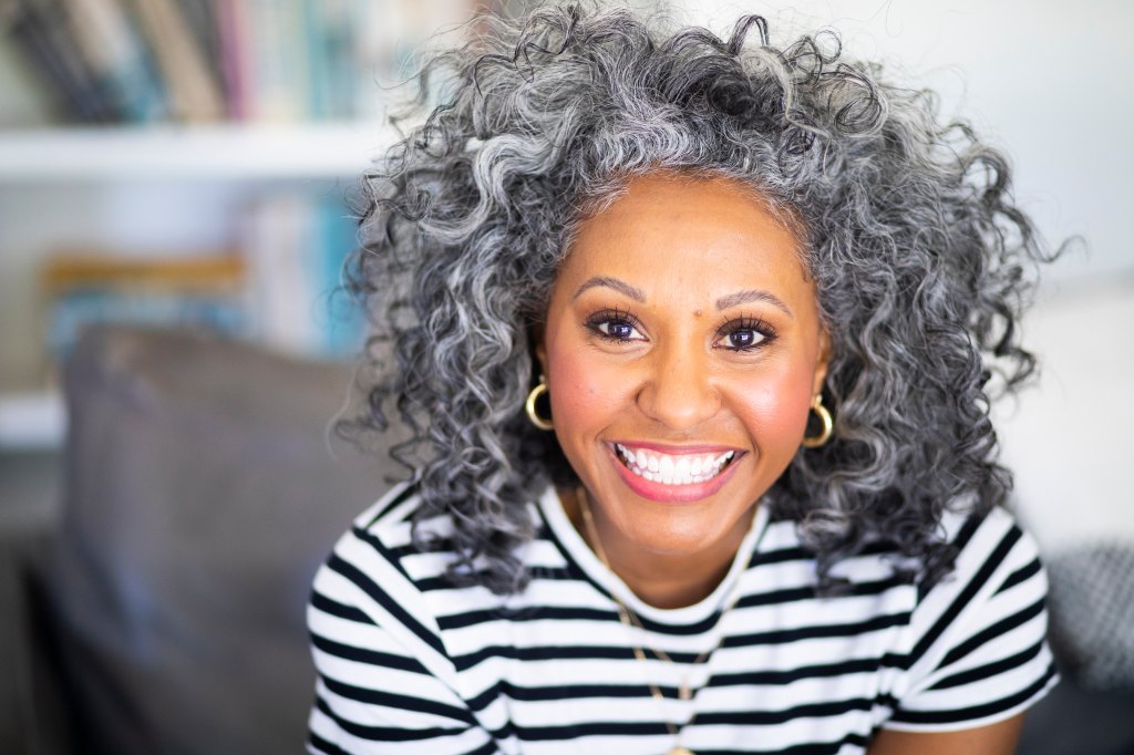 A woman with gray curly hair who is smiling