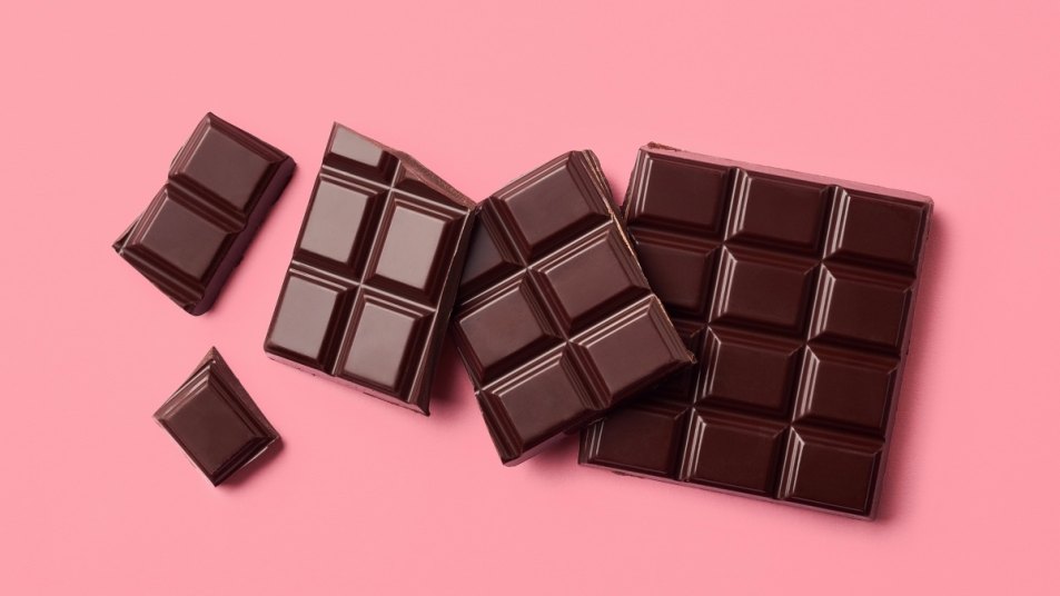 A bar of dark chocolate, which has heart and brain health benefits, against a pink background