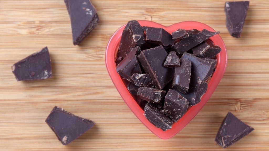 A heart-shaped bowl of dark chocolate against a wood background