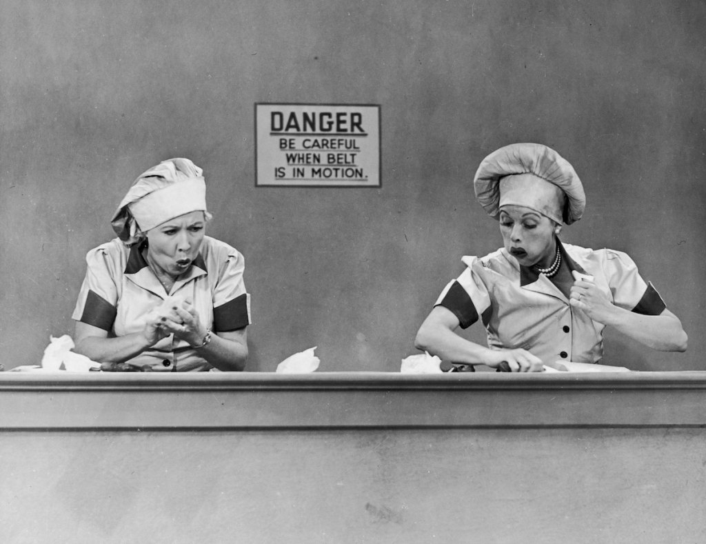 American actresses Vivian Vance (1909 - 1979), as Ethel Mertz, and Lucille Ball (1911 - 1989), as Lucy Ricardo, work side-by side at a candy factory conveyor belt in an episode of the television comedy 'I Love Lucy' entitled 'Job Switching,' Los Angeles, California, May 30, 1952