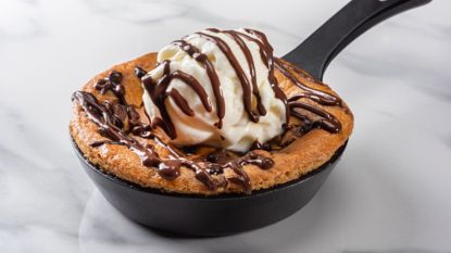 skillet brookie with scoop of vanilla ice cream and chocolate sauce