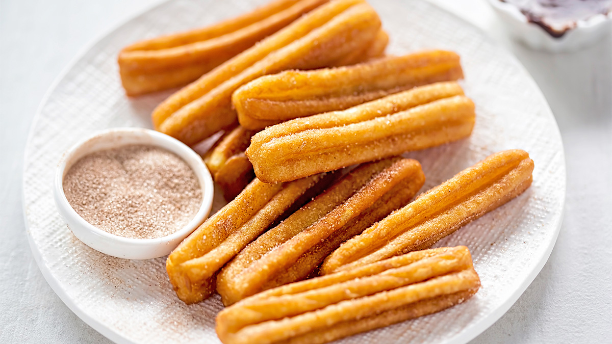 Homemade air fryer churros served on a plate with cinnamon sugar and chocolate sauce