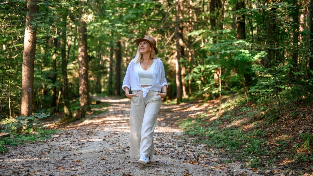 A mature woman wearing a hat while walking through the woods at dusk, which makes her more prone to getting an infected mosquito bite that can lead to cellulitis