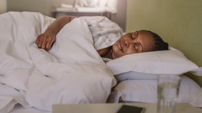 A mature Black woman asleep in bed after taking melatonin