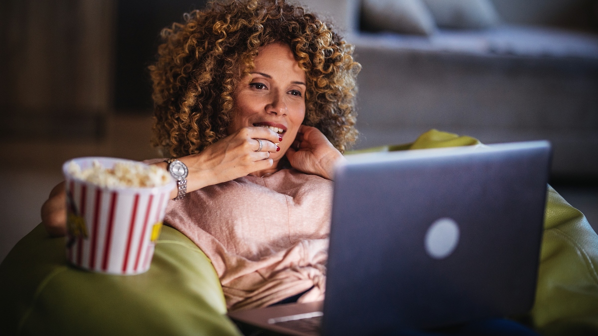 Woman watching a movie on laptop at home, Kanopy
