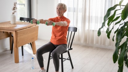 A mature woman doing chair exercises for seniors while in her kitchen