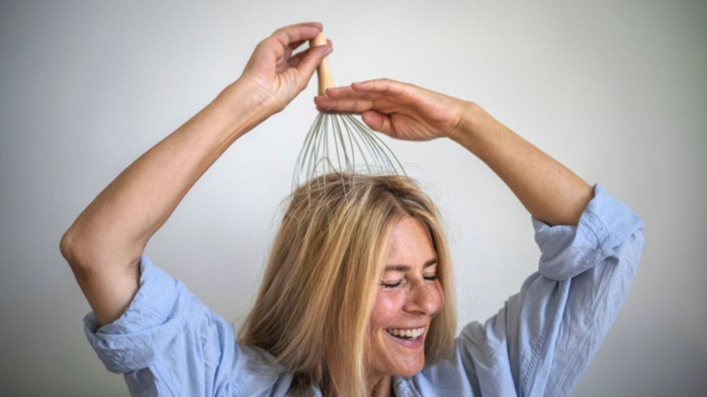 mature woman using a massage tool during scalp massage