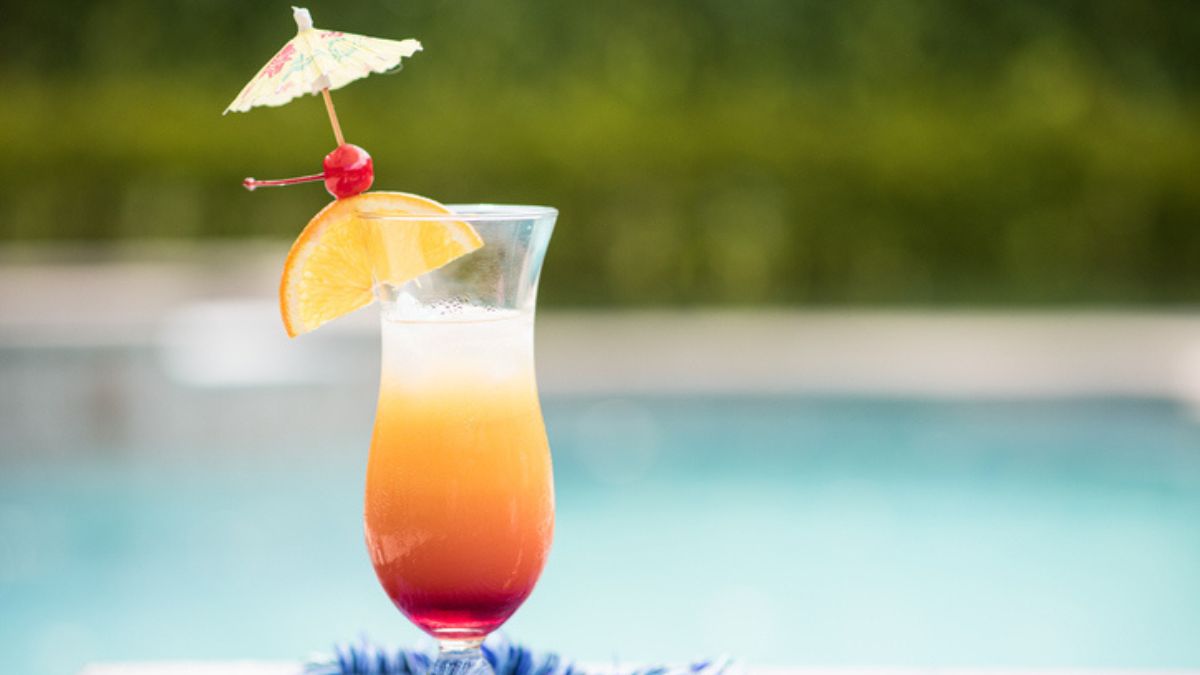 bahama mama cocktail with mini umbrella and garnishes by the pool outside