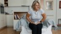 A mature woman sitting on a chair holding her stomach trying to reduce bloating