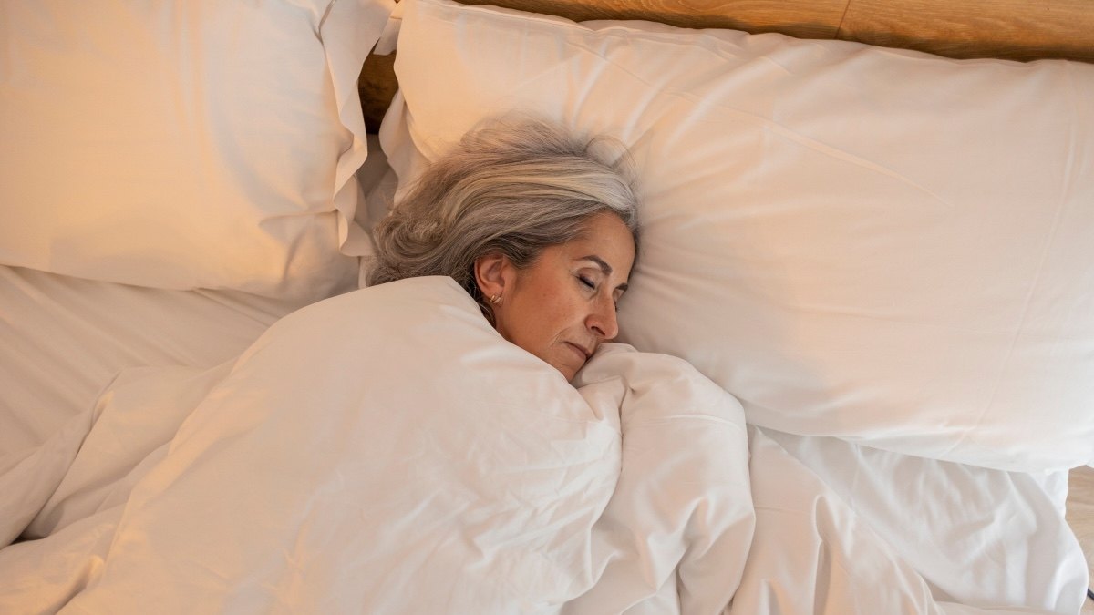 A woman sleeping soundly in bed after trying Andrew Huberman's sleep tricks