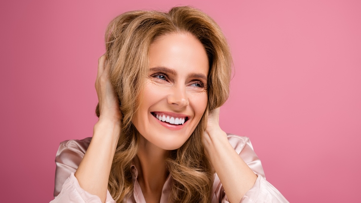 A woman smiling with her hands in her hair after buying Costco products